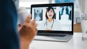 Young woman using computer laptop for video conference call with doctor online consultation.