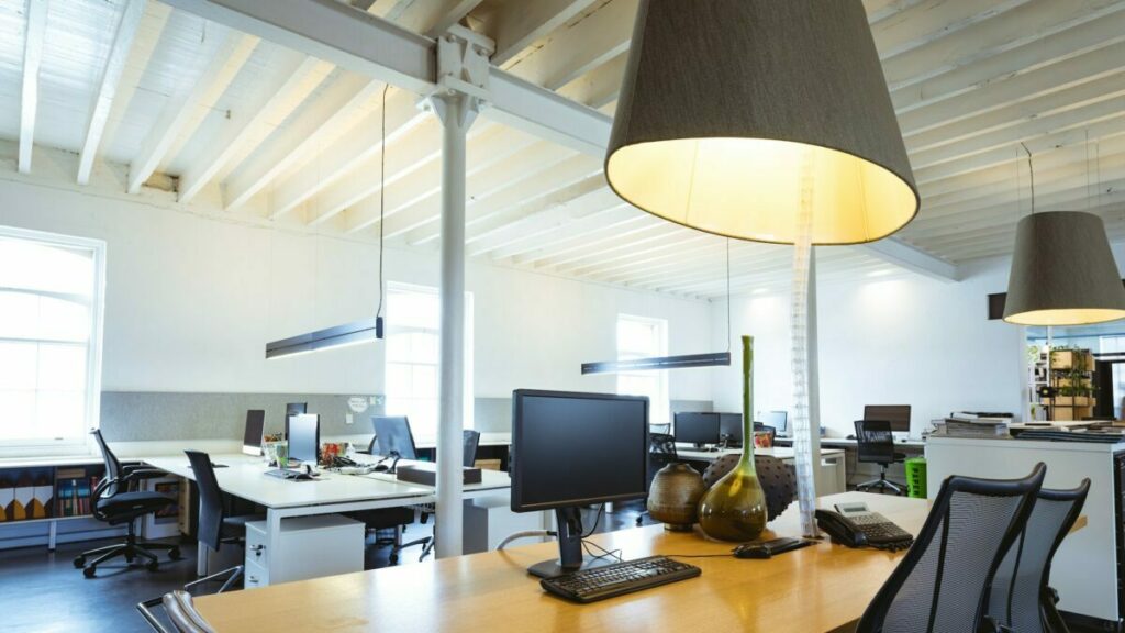 Illuminated pendant light over desk with computers in modern office