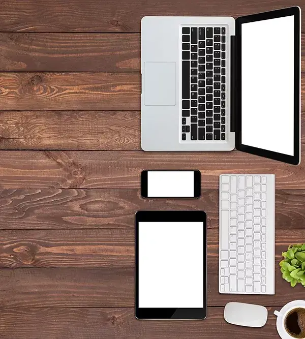 Top view of laptop, keyboard, smart phone and tablet on wooden desktop.