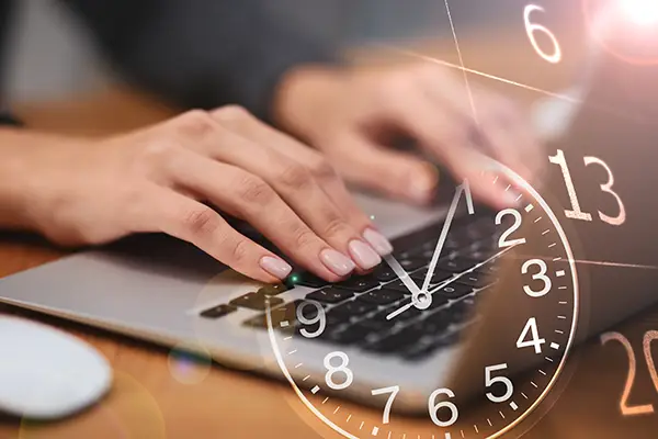 hands typing on a laptop keyboard with clock overlayed on the image.