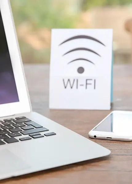 Laptop and mobile device on a desk near a Wifi Sign