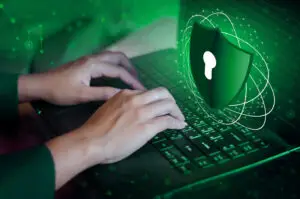 Dark Green background, with hands using laptop with computer firewall security logo floating above the keyboard.